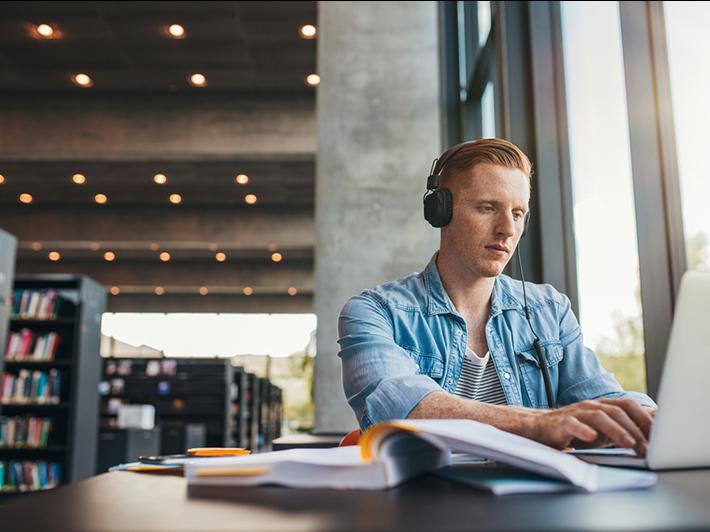 Young male university student in library