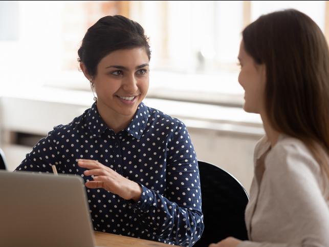 Two women discuss over a laptop
