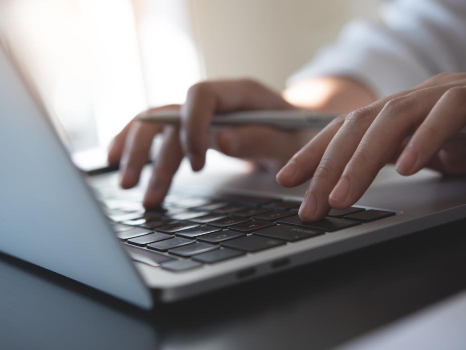 Hands typing on a laptop keyboard