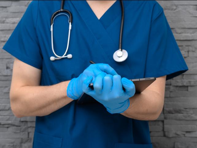 A doctor takes notes on a clipboard