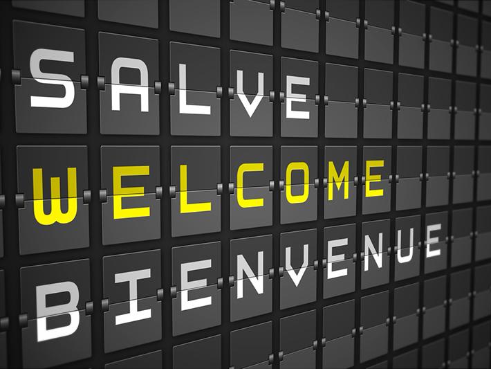 Airport arrival sign with welcome in English, French and Italian
