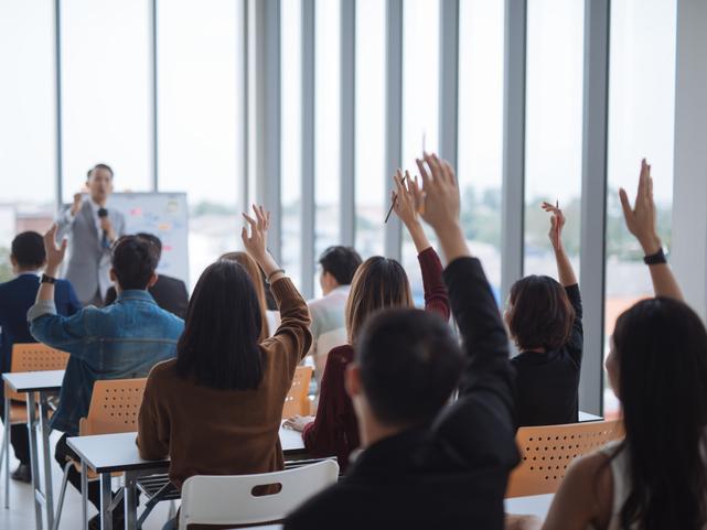 Students raise their hands in a lecture hall