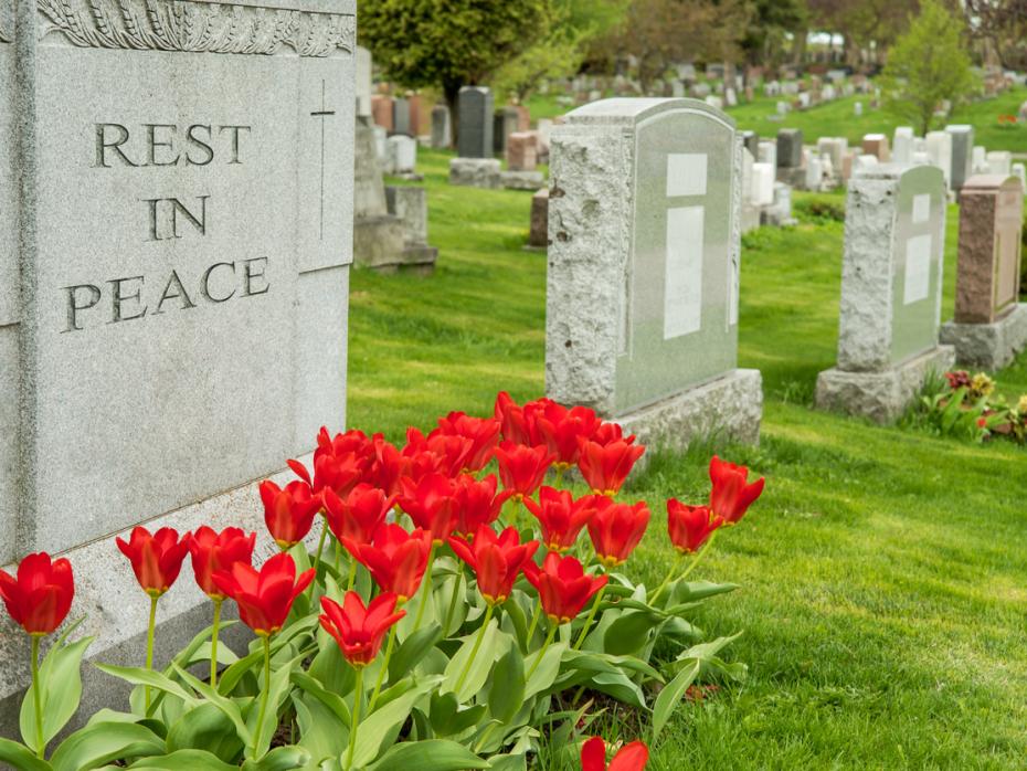 A tombstone in a graveyard with the words "rest in peace" carved into it