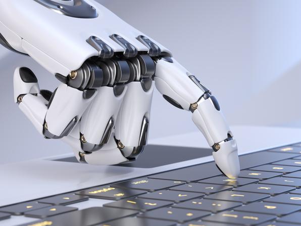 A robot hand presses a key on a laptop keyboard
