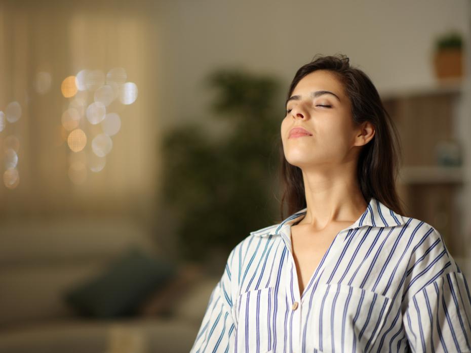 A woman inhaling with her eyes closed