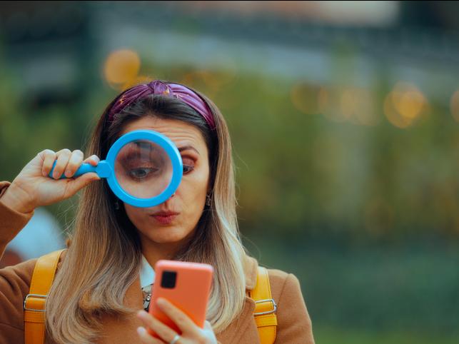 A woman uses a magnifying glass to check her phone
