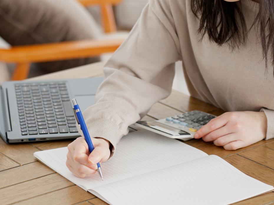 An unseen woman doing sums with a calculator