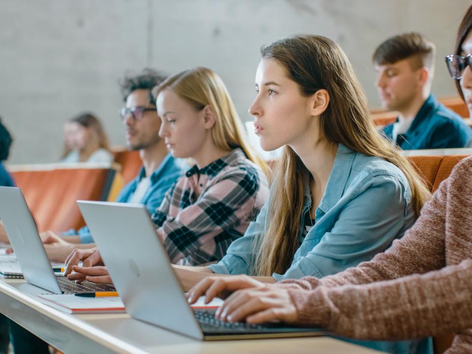 Students in a lecture hall typing on their laptops