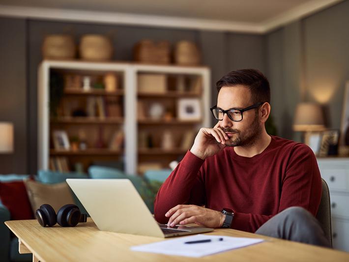 Young male student looking thoughtfully at a laptop