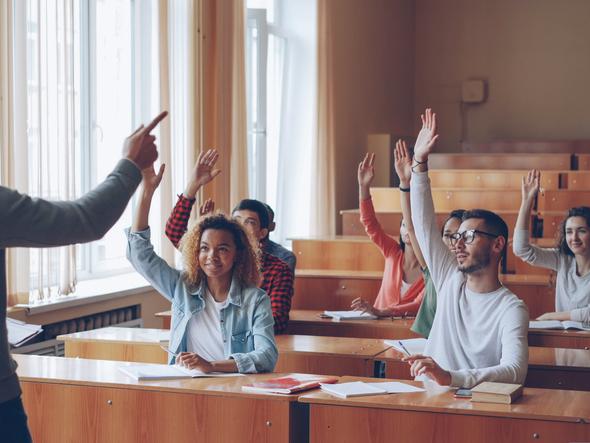 Students raise their hands in a lecture hall