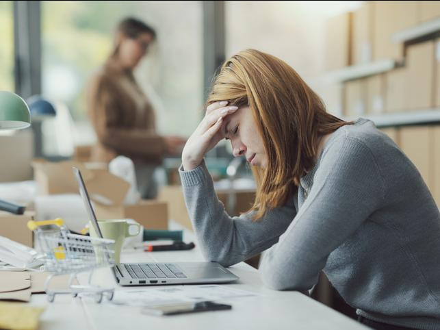 A young woman puts a hand to her head while working at an office
