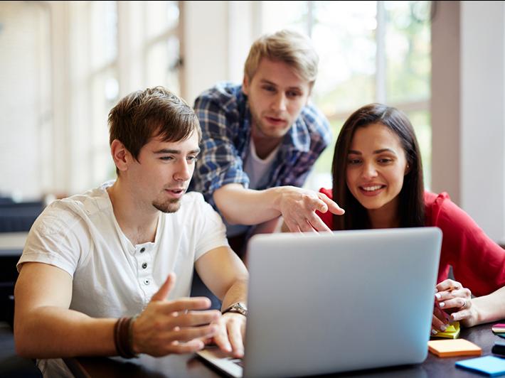 Young male teaching assistant with two college students