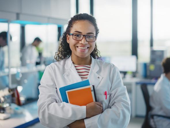 A student in a lab coat smiles