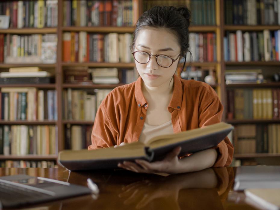 A woman researching at a desk in a library