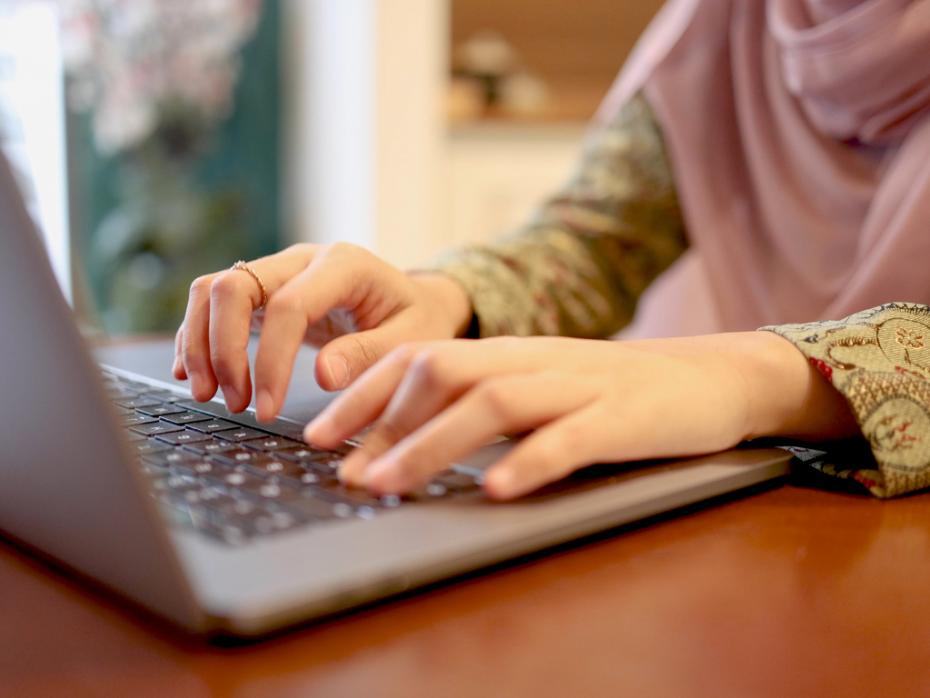 An unseen person at a laptop typing