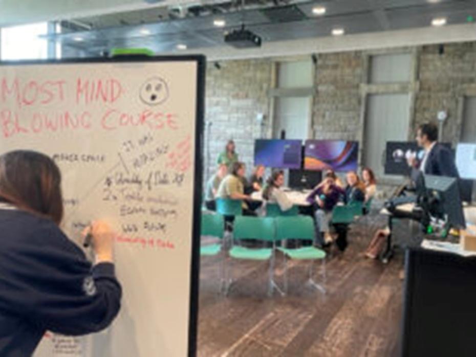 A student responding to a prompt on a whiteboard during 2024's Feedback Fest