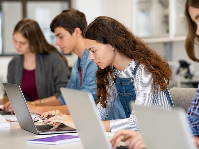 Students use their laptops in class, looking focused