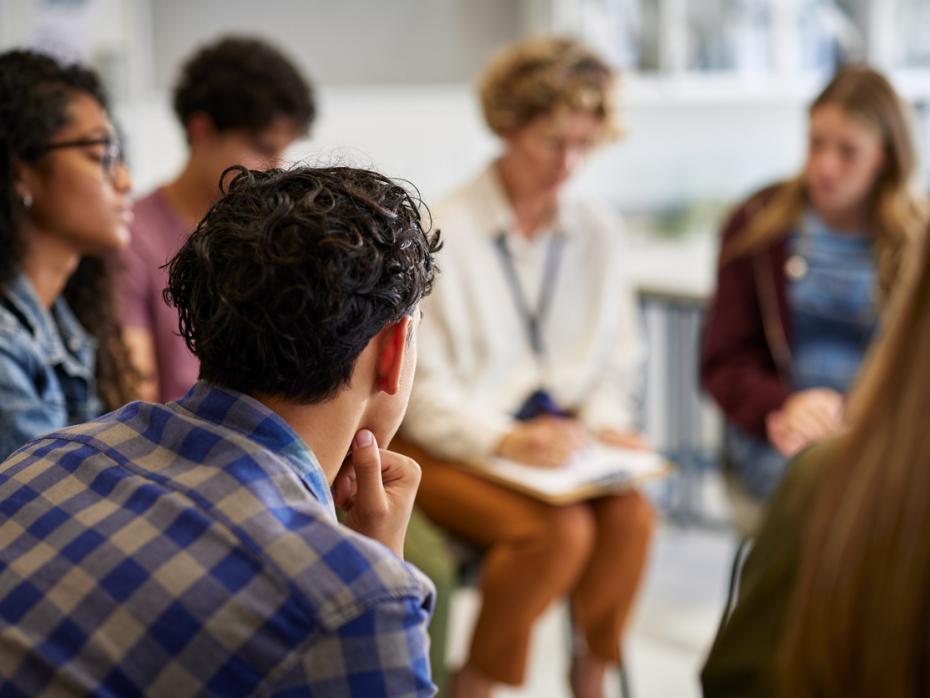 Students sitting in a circle haveing a discussion with a teacher