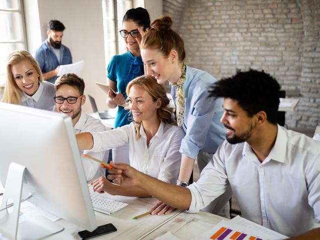 Students work together around a desktop computer