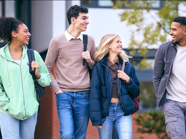 Group of four smiling college students walking