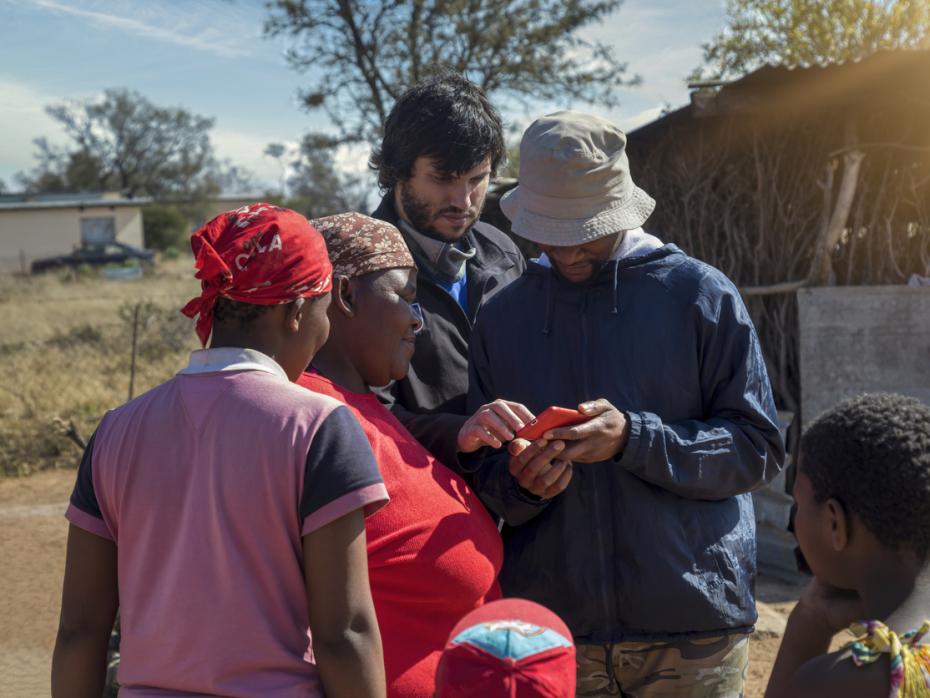 Group of people in Kenya, looking at a mobile phone