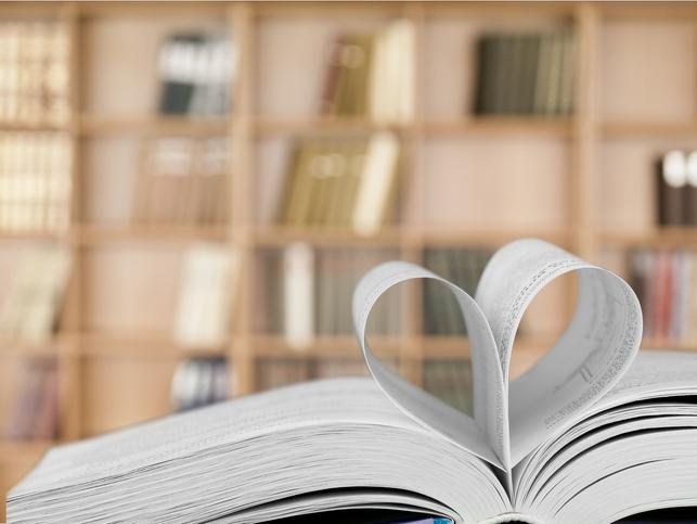 A book with heart-shaped pages in front of a stacked bookcase