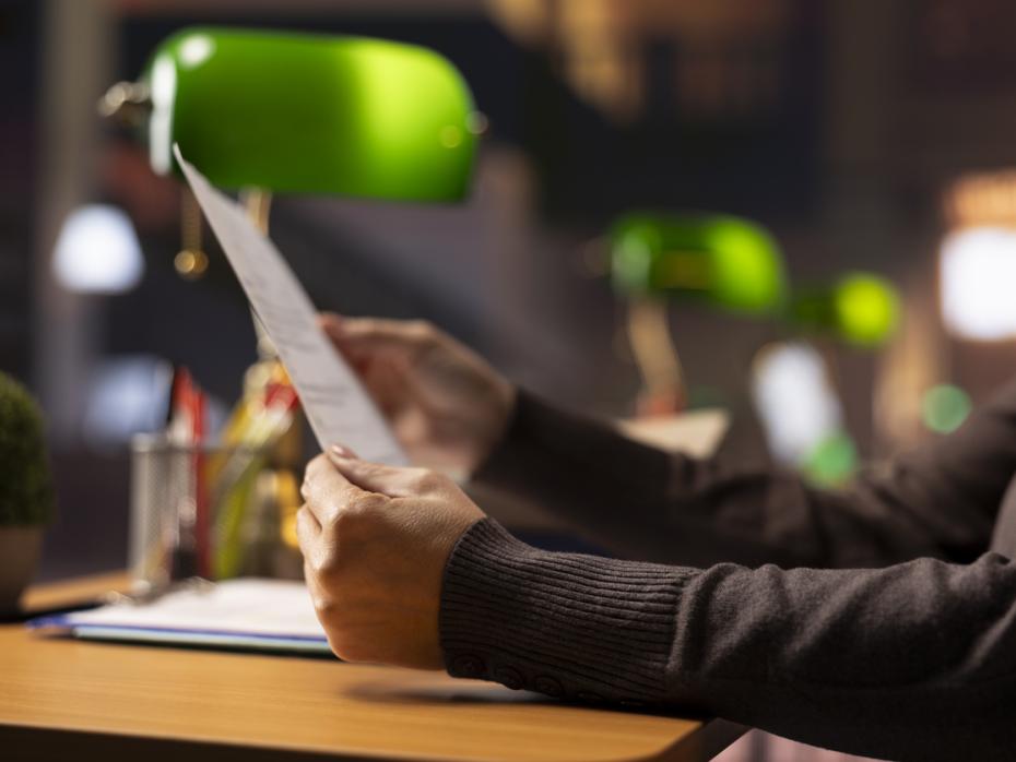 A professor holding a document in a library