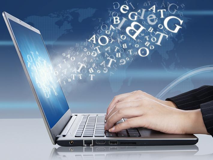 Laptop with cloud of letters coming out of screen