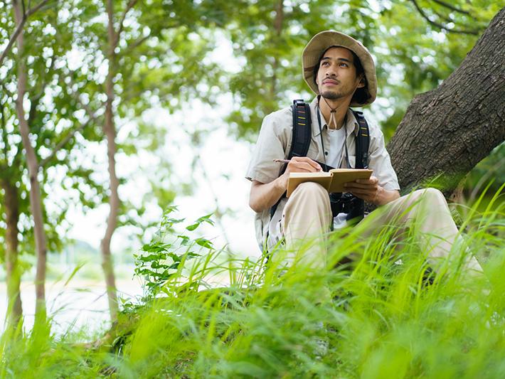 Young Asian man recording observations in nature