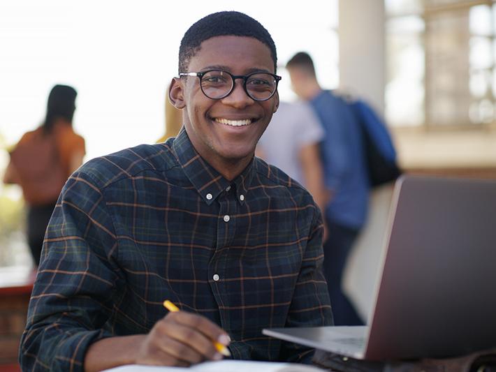 Young black male students working outside on laptop