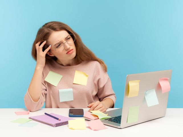 A student sits in front of a laptop, covered in Post-It notes