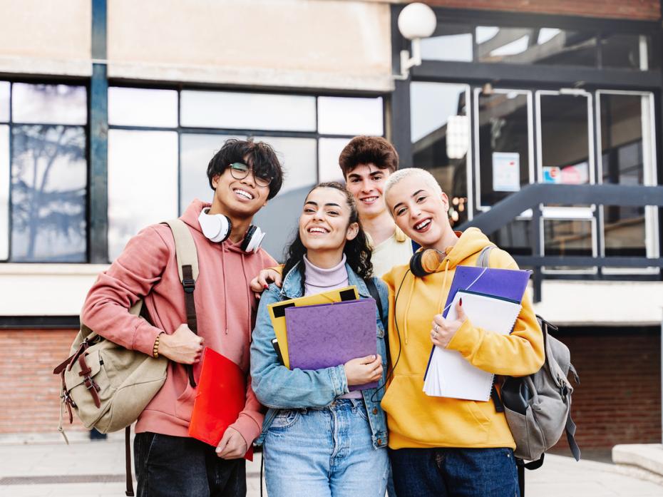 A group of smiling university students outside a campus building