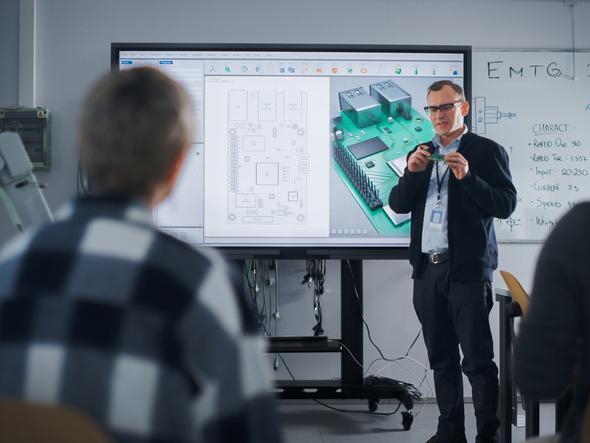 A teacher explains a circuit board to a class