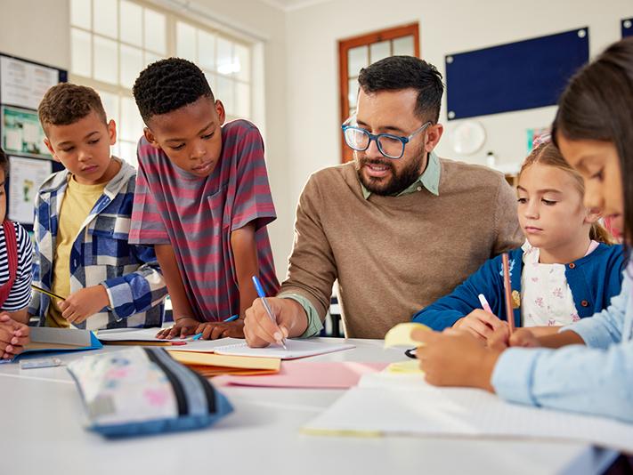 Male teacher working with multiracial primary school class