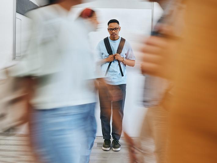Black male student looking downcast in university corridor