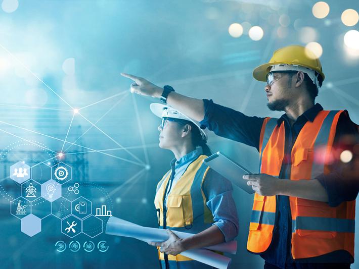 A male and female engineer in safety gear pointing at project