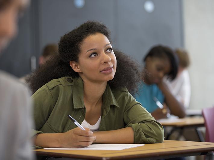 Black female student looking thoughtful writing