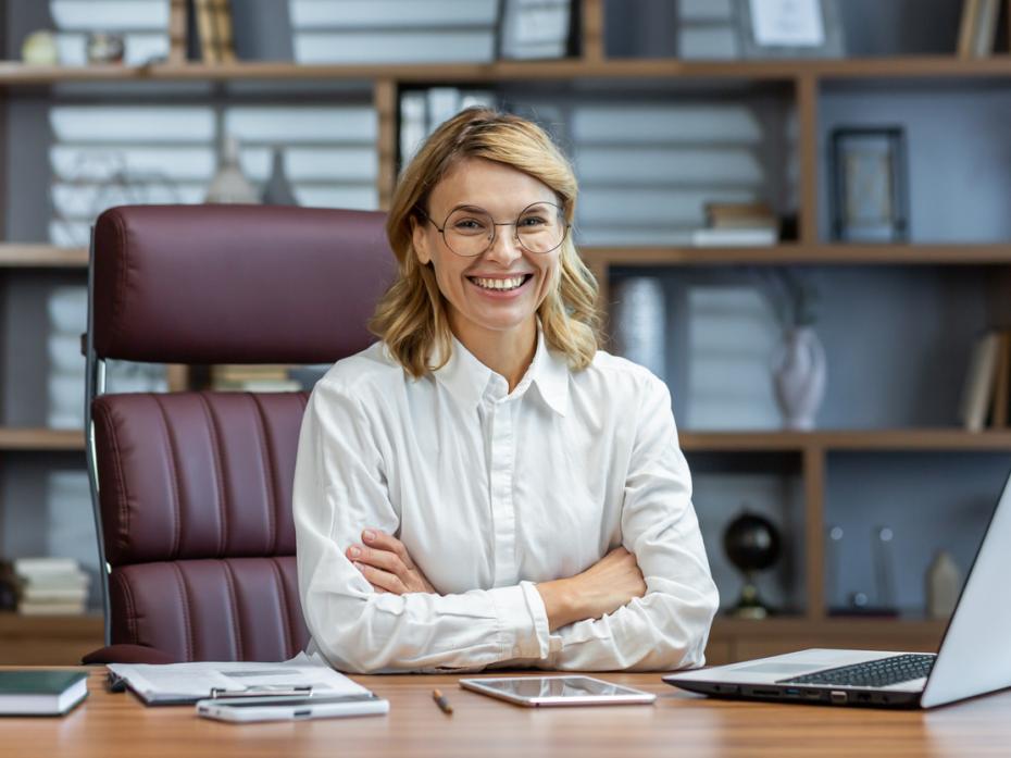 A research supervisor sitting at her desk smiling to camera