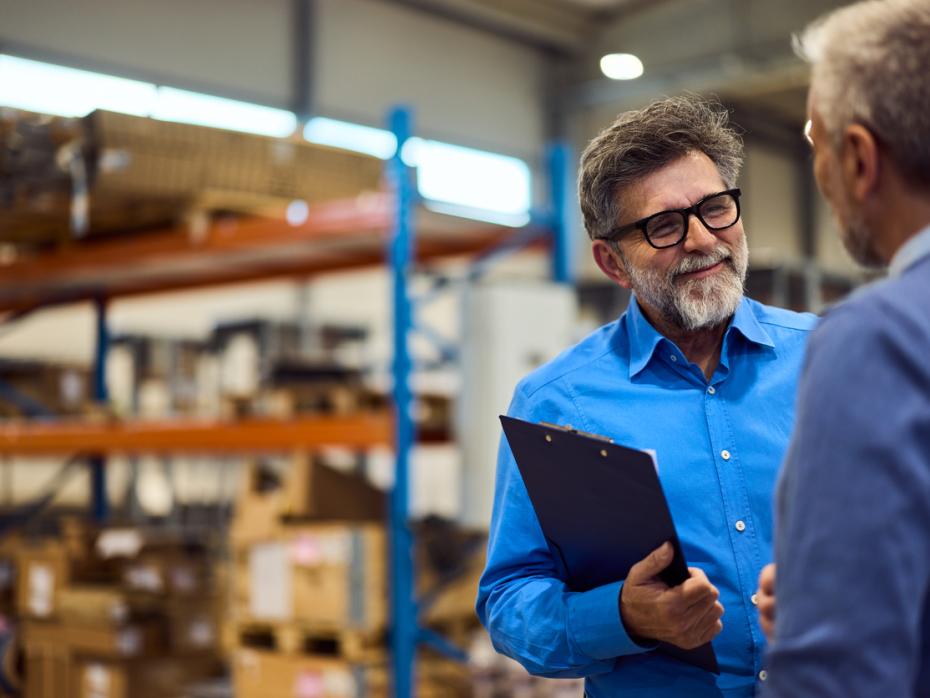 A businessman in a warehouse speaks to a business partner.