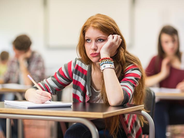 Red-headed female student looking unhappy in an exam