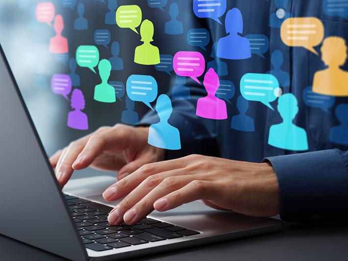 Man's hands over laptop keyboard with figures and speech bubbles