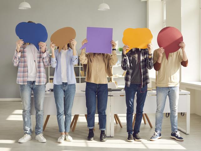 Students hold brightly coloured speech bubbles up to their faces