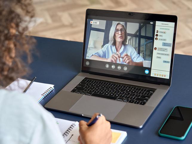 A student watches a teacher lecture on a laptop