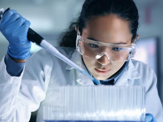 A close up of a researcher in a lab filling a test tube 