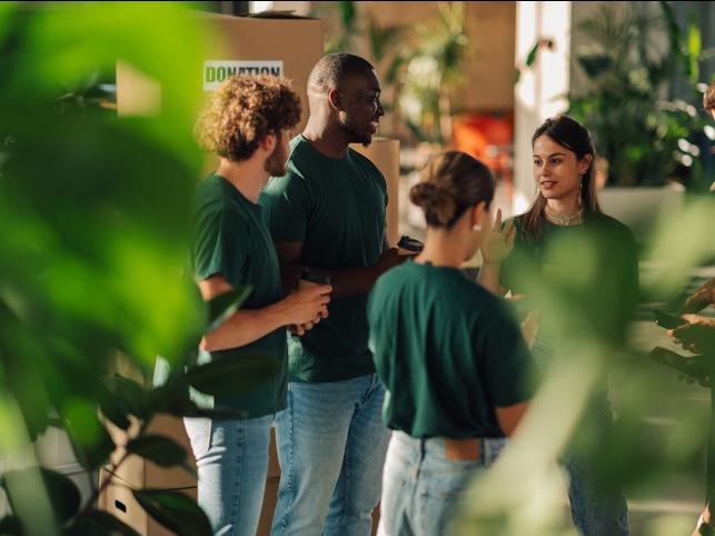 A group of students wearing green t shirts discussing a sustainability initiative