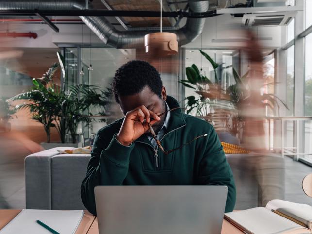 A man at a desk rubs his forehead
