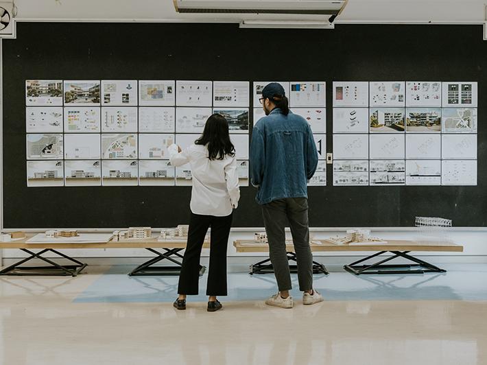 Architecture students inspecting plans on a board