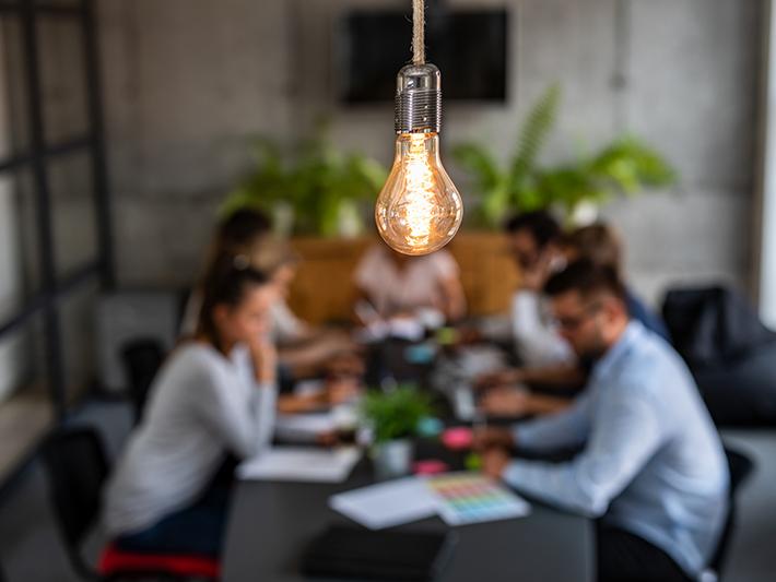 Team meeting with lightbulb in foreground