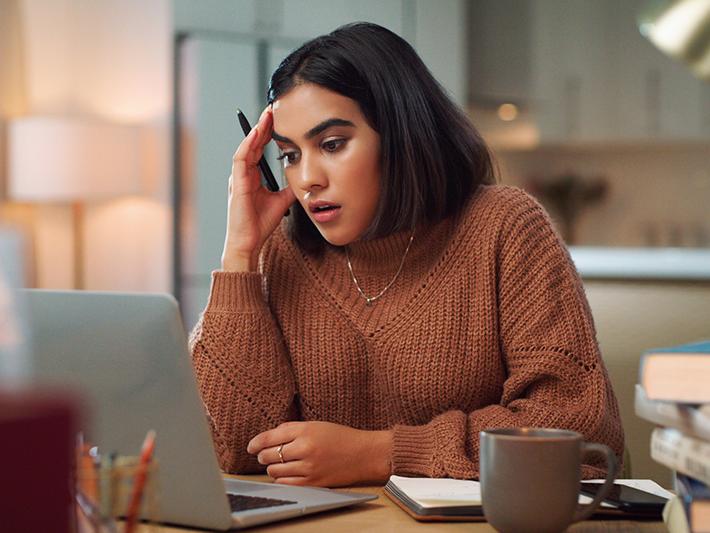 Young female student looking confused at laptop
