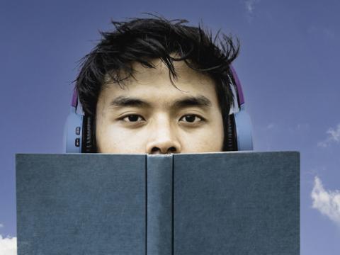 Young man in headphones holding a book